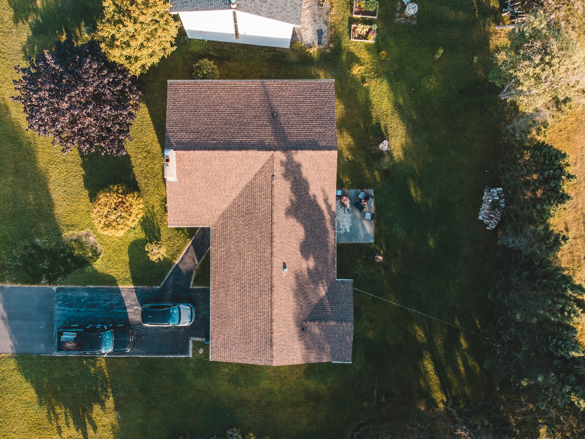 Top-down aerial view of a shingled house roof and property captured by drone
